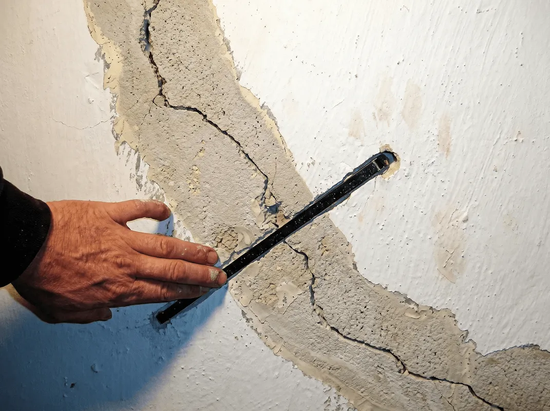 A wall with a large crack is being inspected by a professional in Boise, ID