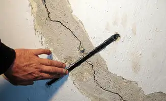 A wall with a large crack is being inspected by a professional in Boise, ID